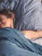Una persona che dorme serenamente nel proprio letto con affiancata la confezione di Valens per il sonno naturale.